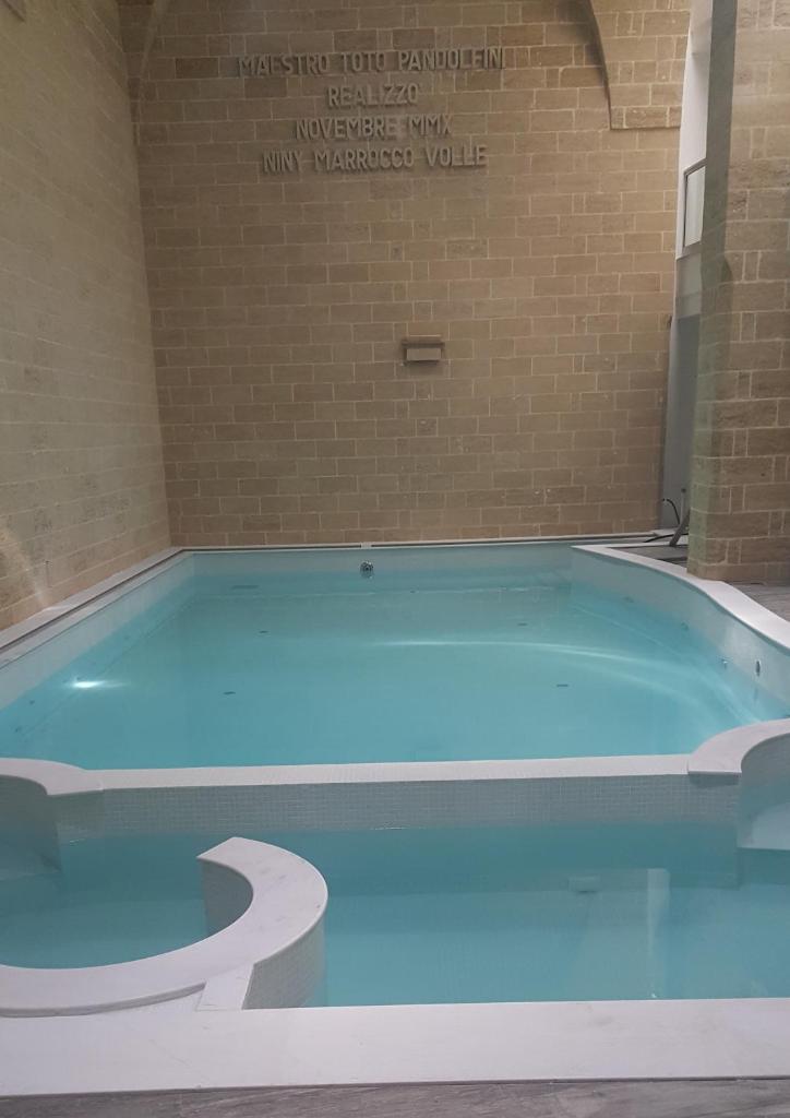 - une grande piscine bleue dans une pièce dotée d'un mur en briques dans l'établissement La Corte di Leuca Residence, à Leuca