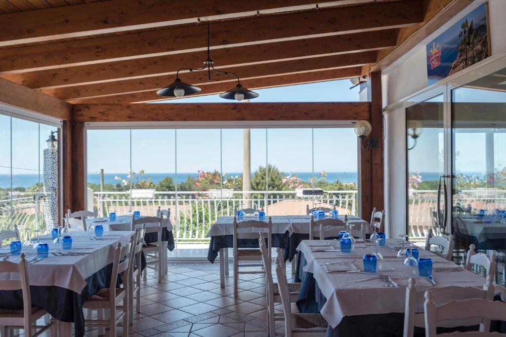 une salle à manger avec tables, chaises et fenêtres dans l'établissement Hotel Ristorante Colleverde, à Santa Maria di Castellabate