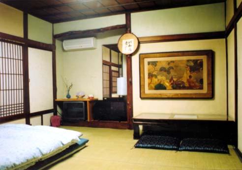une chambre avec un lit et une horloge au mur dans l'établissement Tama Ryokan, à Tokyo