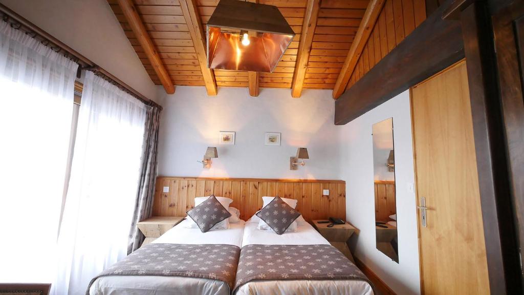 une chambre avec deux lits et une grande fenêtre dans l'établissement L'Annexe, à Val dʼIsère