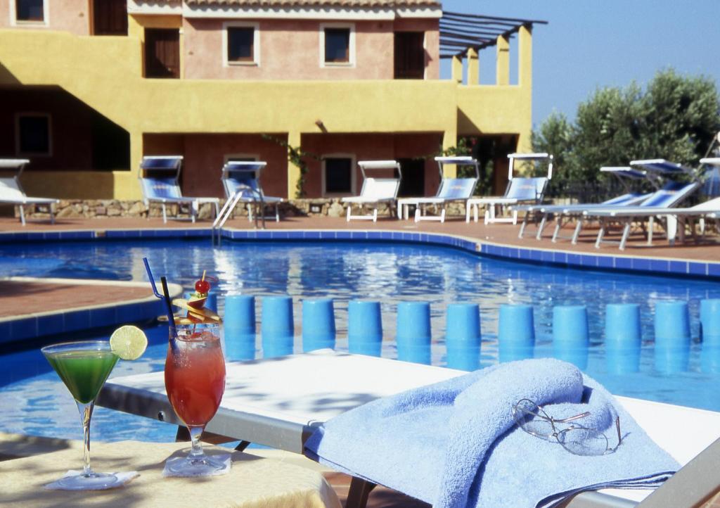 - une table avec deux boissons à côté de la piscine dans l'établissement Hotel Stelle Marine, à Cannigione