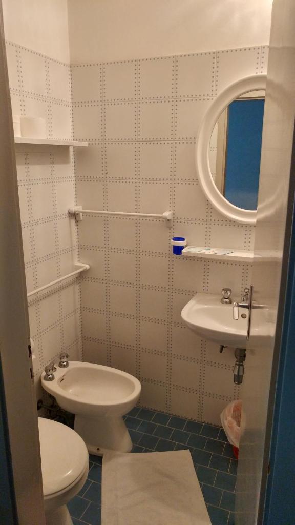 une salle de bain avec un lavabo, des toilettes et un miroir dans l'établissement Hotel Biagini, à Rimini