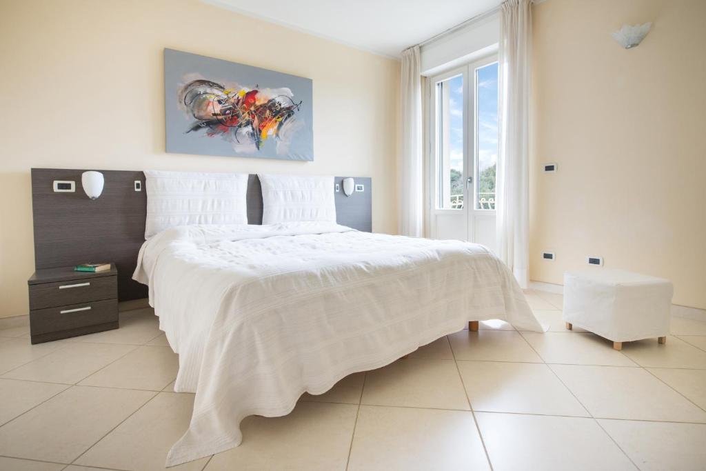 - une chambre blanche avec un lit blanc et un tableau dans l'établissement Residence Colombo, à Viareggio