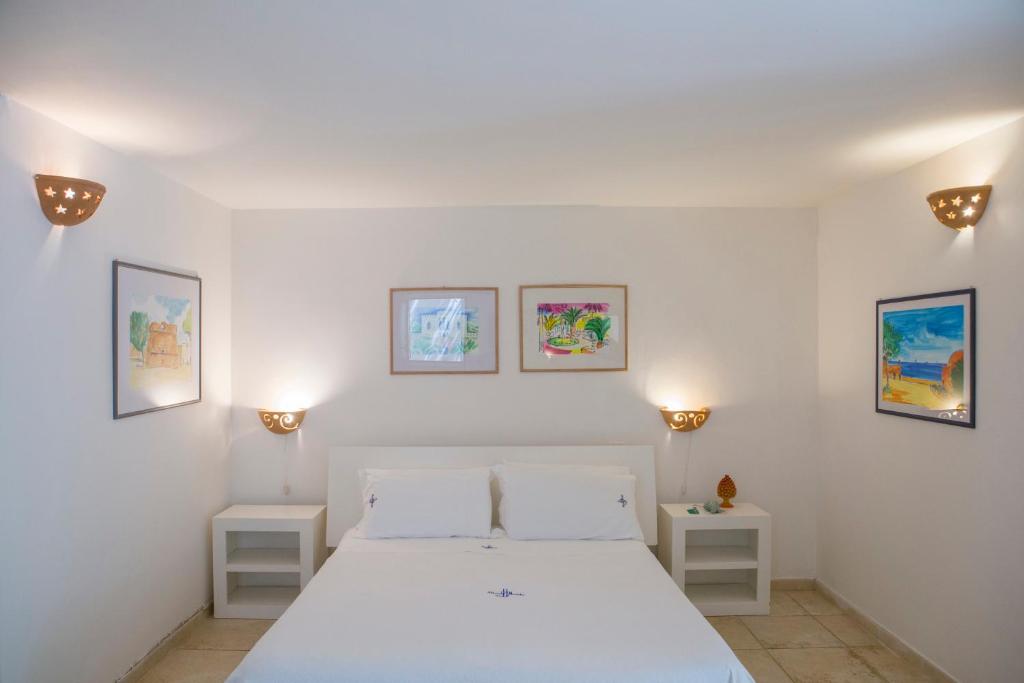 une chambre avec un lit blanc et trois tableaux au mur dans l'établissement Hotel Piccolo Mondo, à Castro di Lecce