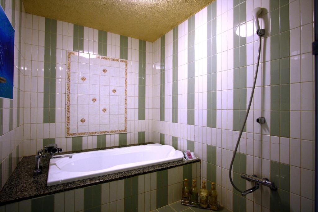 une salle de bain avec une baignoire et un miroir dans l'établissement Hotel Ohirune Racco Higashiosaka ( Adult Only), à Higashiōsaka
