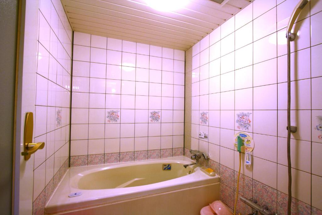 une salle de bain avec baignoire et murs carrelés de rose dans l'établissement Hotel Ohirune Racco Himeji Royal (Adult Only), à Himeji
