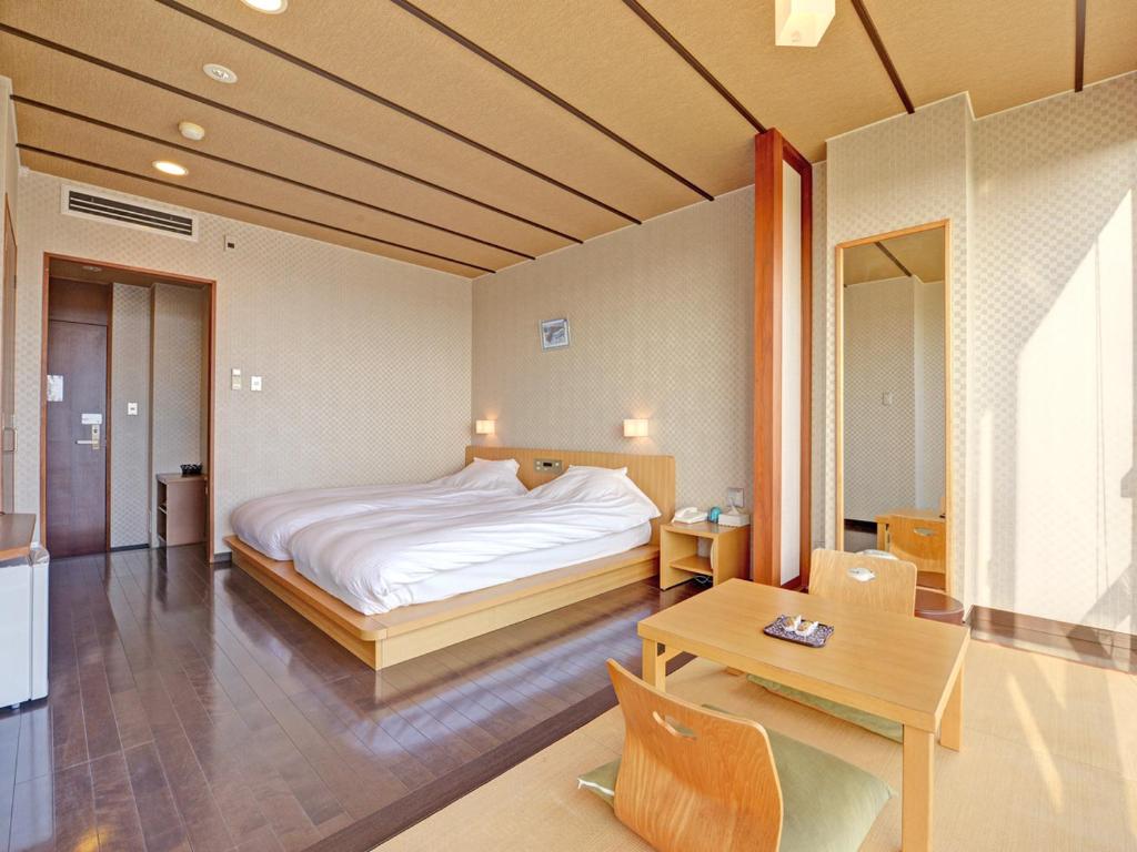 une chambre avec un lit et une table dedans dans l'établissement Iioka Shiosai Hotel, à Asahi