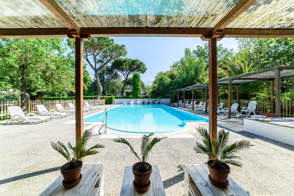 une piscine avec une pergola et des palmiers dans l'établissement Hotel La Bussola, à Marina di Massa
