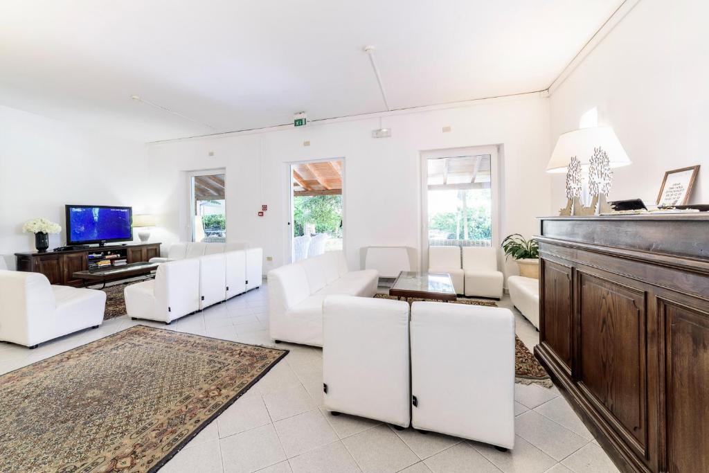 un salon avec des meubles blancs et une télévision à écran plat dans l'établissement Hotel La Bussola, à Marina di Massa