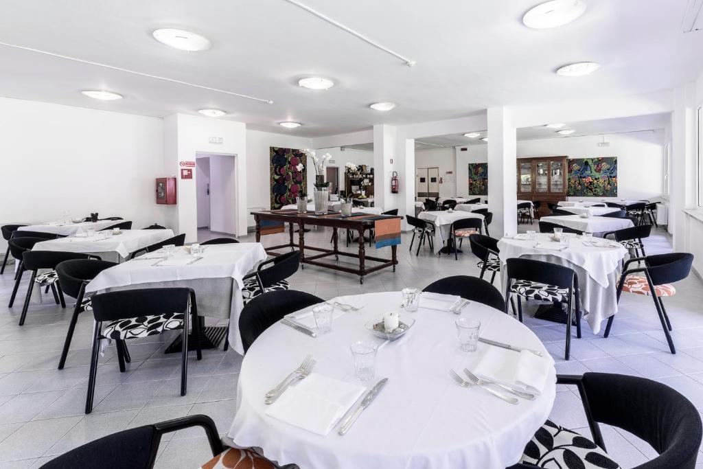 une salle à manger avec des tables blanches et des chaises noires dans l'établissement Hotel La Bussola, à Marina di Massa