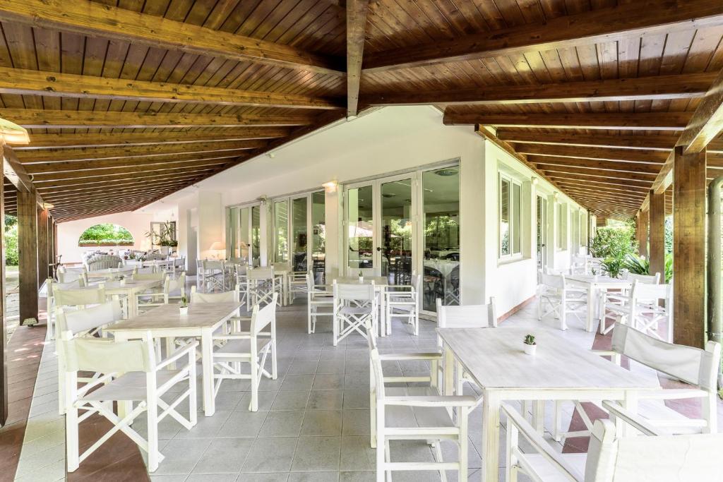 un restaurant avec des tables et des chaises blanches sur la terrasse dans l'établissement Hotel La Bussola, à Marina di Massa
