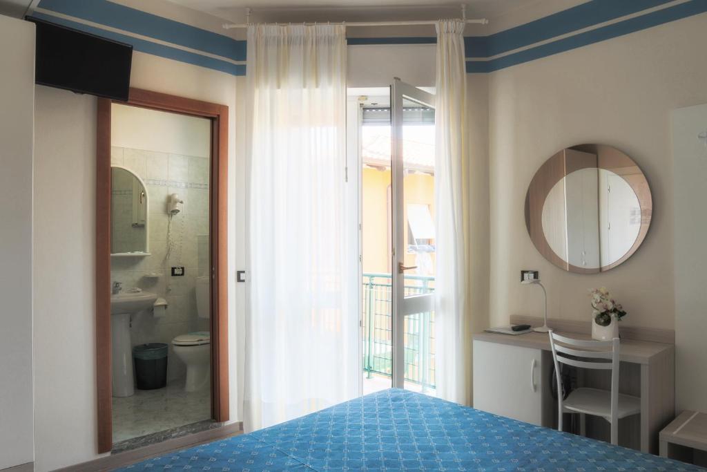 une chambre avec un lit et une salle de bains avec un miroir dans l'établissement Hotel Orchidea, à Lignano Sabbiadoro