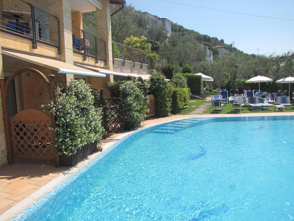 - une piscine en face d'un bâtiment avec des chaises dans l'établissement Residence Rosemary, à Brenzone