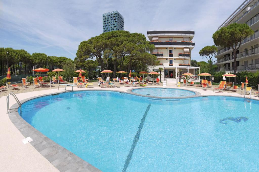 une grande piscine avec chaises et parasols dans l'établissement Hotel Bertha Fronte Mare, à Lido di Jesolo