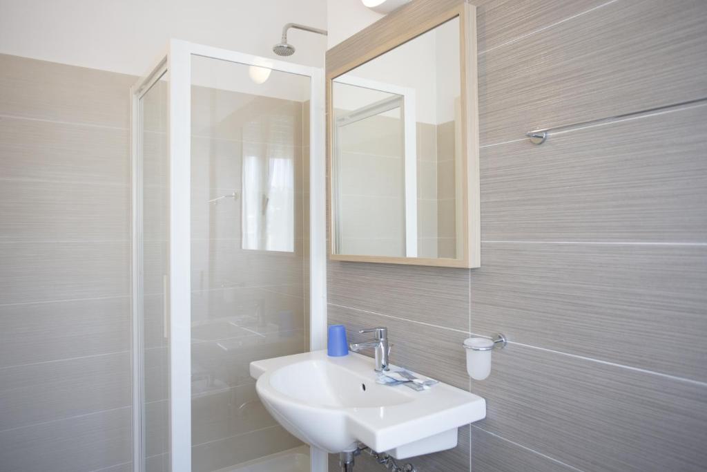 une salle de bain avec un lavabo, un miroir et une douche dans l'établissement Hotel Tiberius, à Rimini 16 autres photos