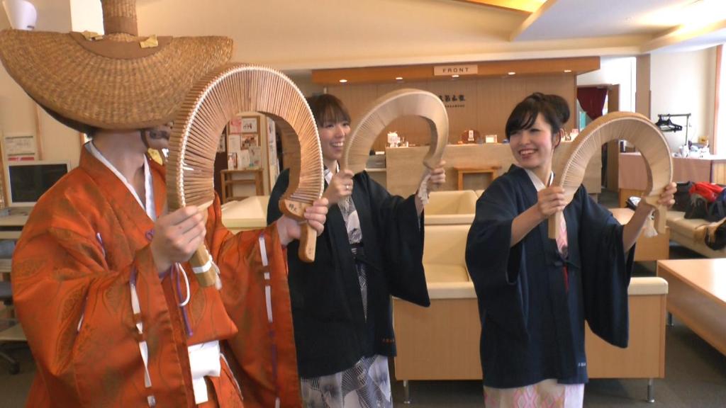 un groupe de trois jeunes tenant des parapluies dans l'établissement Gokasanso, à Nanto