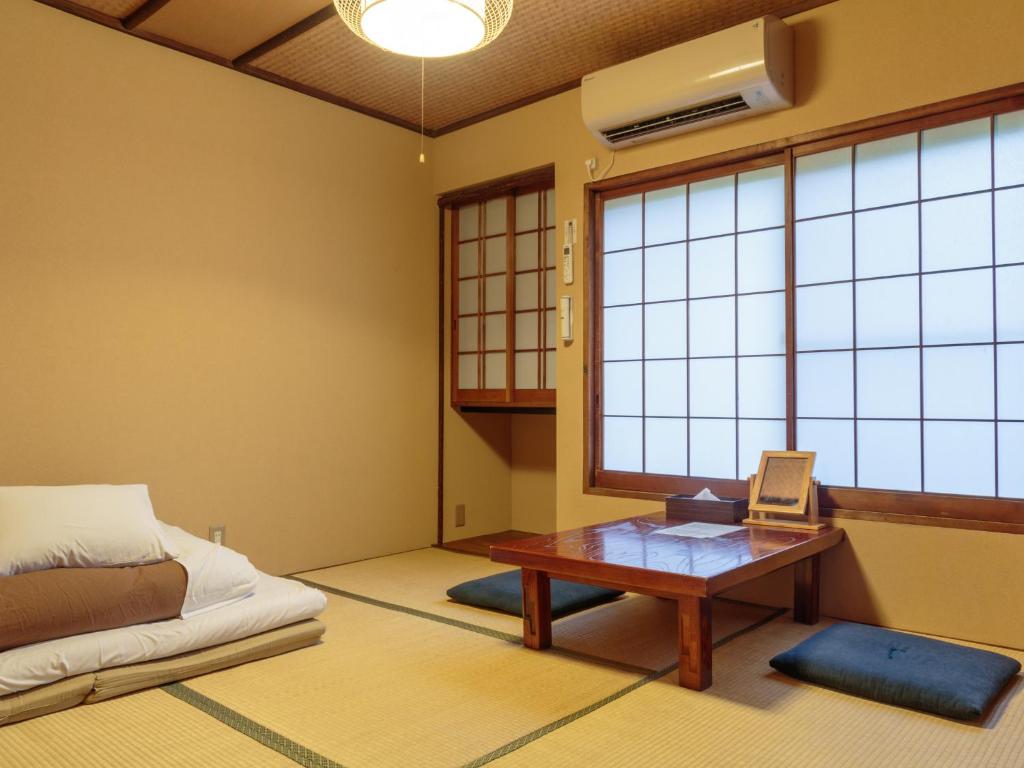 Cette chambre comprend une table, un lit et une fenêtre. dans l'établissement Gion Ryokan Q-beh, à Kyoto