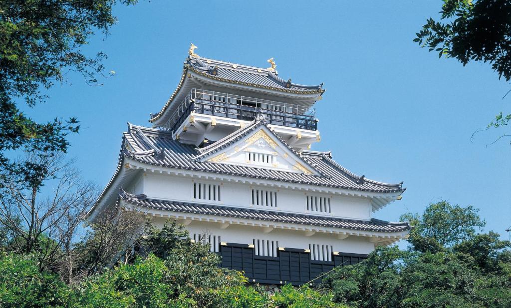 un grand bâtiment blanc avec des arbres devant dans l'établissement ホテル Tiger & Dragon 男塾ホテルグループ, à Gifu