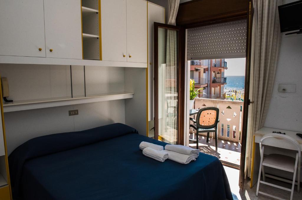 - une chambre avec un lit bleu et une vue sur l'océan dans l'établissement Hotel Malibran, à Lido di Jesolo