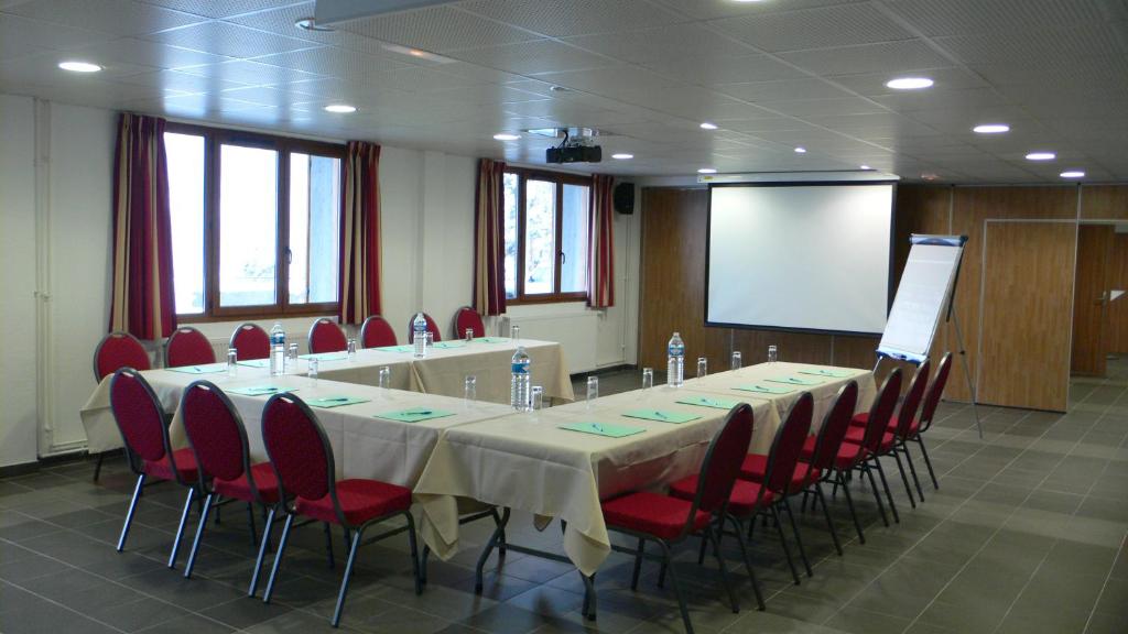une salle de conférence avec une longue table et des chaises rouges dans l'établissement Residence Adrechas et Spa, à La Colmiane