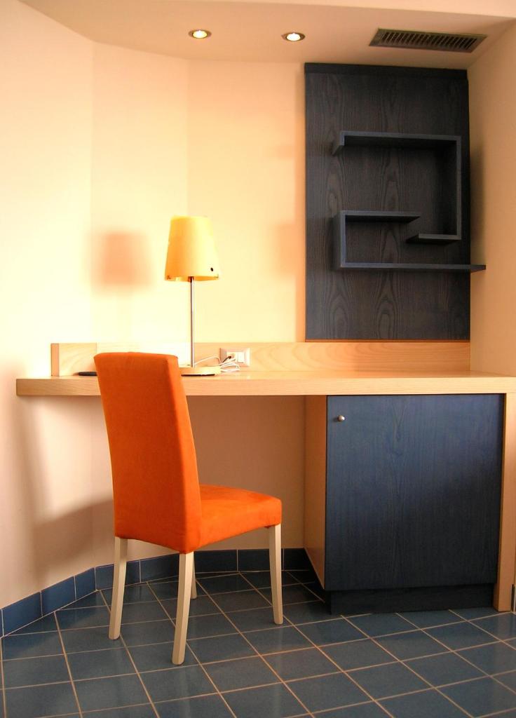 une chaise orange assise à un bureau dans une pièce dans l'établissement Torre Del Sole, à Terracine