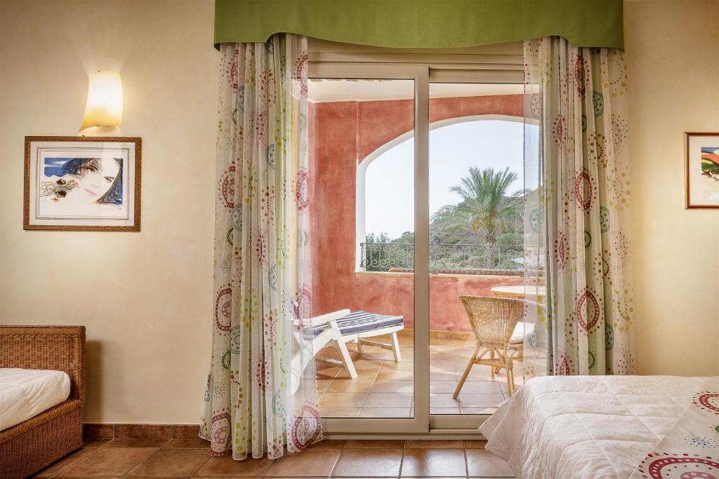 une chambre avec un lit et une porte coulissante en verre dans l'établissement Cruccùris Resort - Adults Only, à Villasimius 112 autres photos