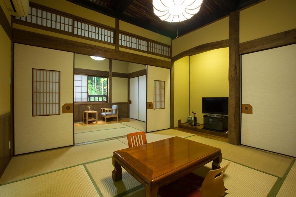 - un salon avec une table en bois et une télévision dans l'établissement Oogi Onsen Oogiso, à Minamioguni