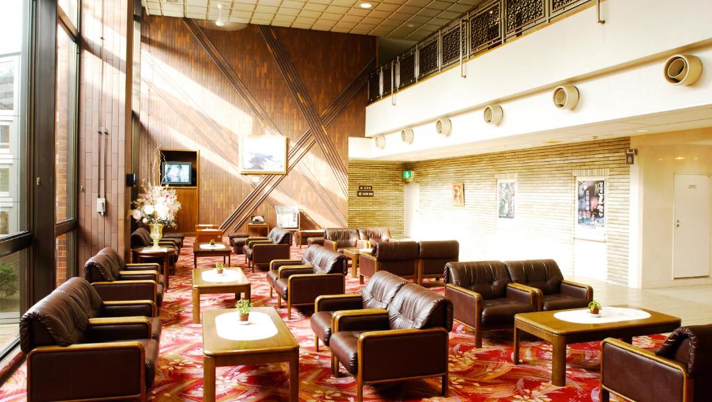 une salle d'attente avec des chaises et des tables en cuir dans l'établissement Kasugai View Hotel, à Fuefuki