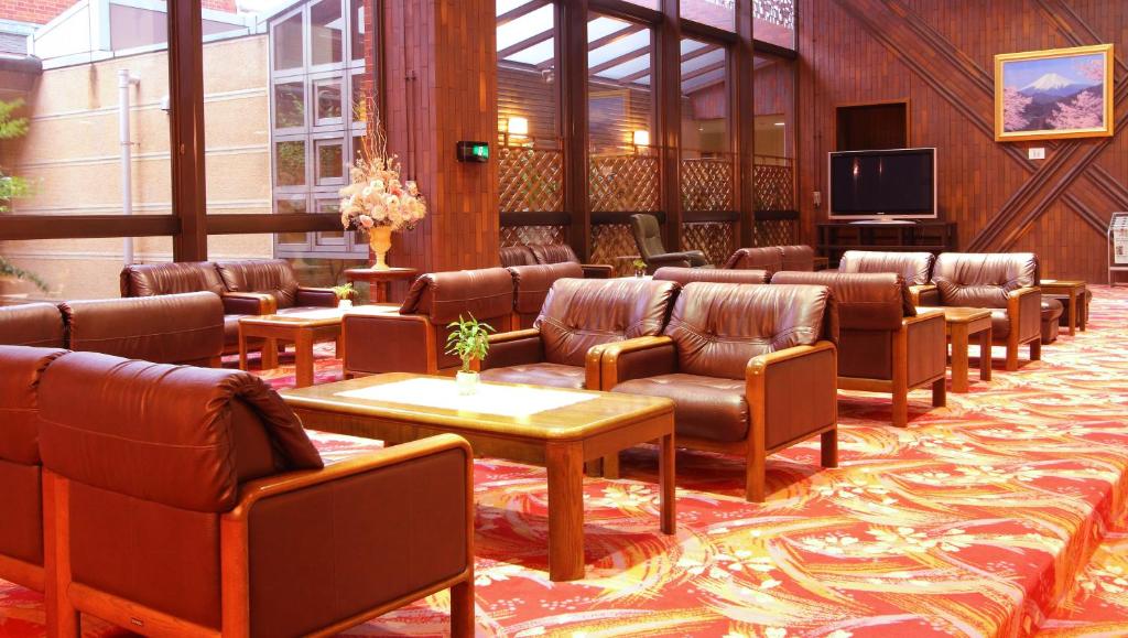 une salle d'attente avec des fauteuils en cuir et une télévision à écran plat dans l'établissement Kasugai View Hotel, à Fuefuki
