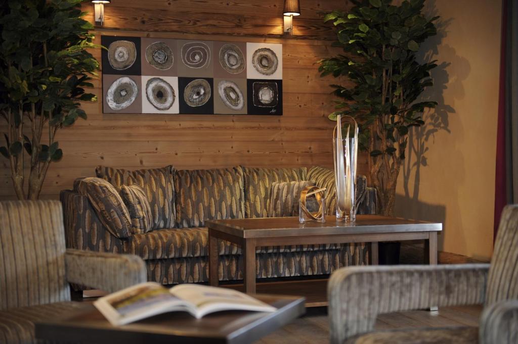 - un salon avec un canapé et une table avec un livre dans l'établissement CGH Résidences & Spas Le Jhana, à Tignes