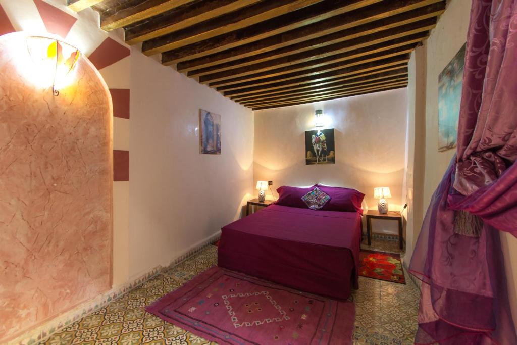 - une chambre avec un lit violet dans l'établissement Riad Diwan, à Fès