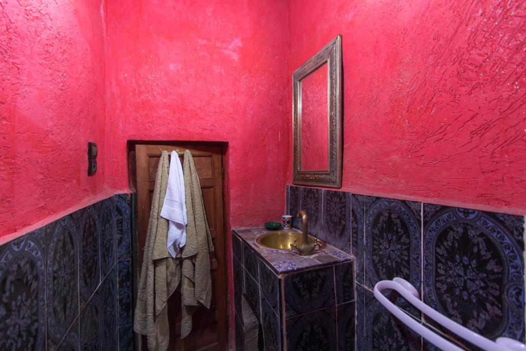 La salle de bains est pourvue d'un lavabo et d'un mur rouge. dans l'établissement Riad Diwan, à Fès