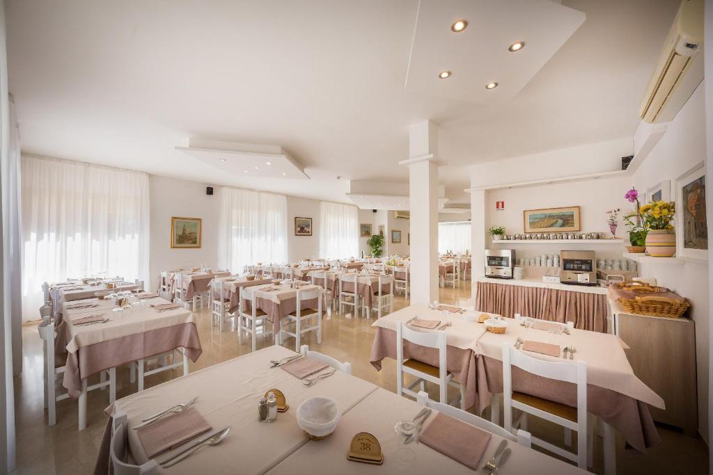 une salle à manger avec des tables blanches et des chaises blanches dans l'établissement Hotel Augusta, à Caorle