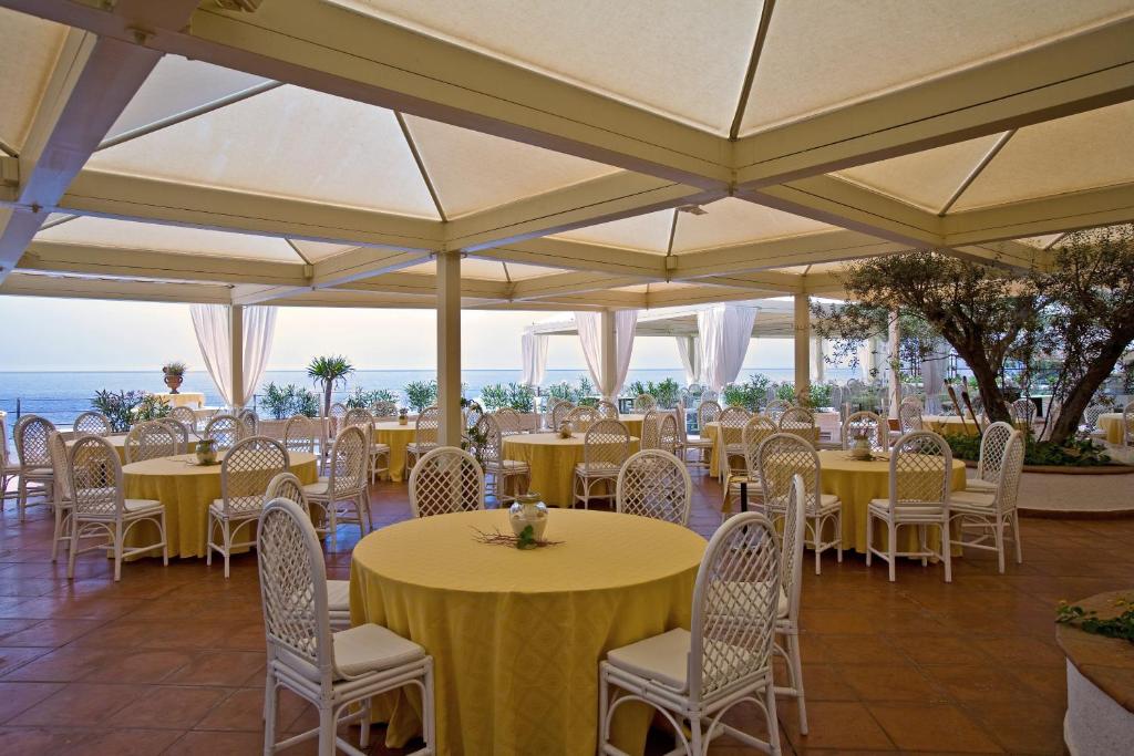 un restaurant avec des tables et des chaises jaunes et l'océan dans l'établissement Grand Hotel Baia Verde, à Catane