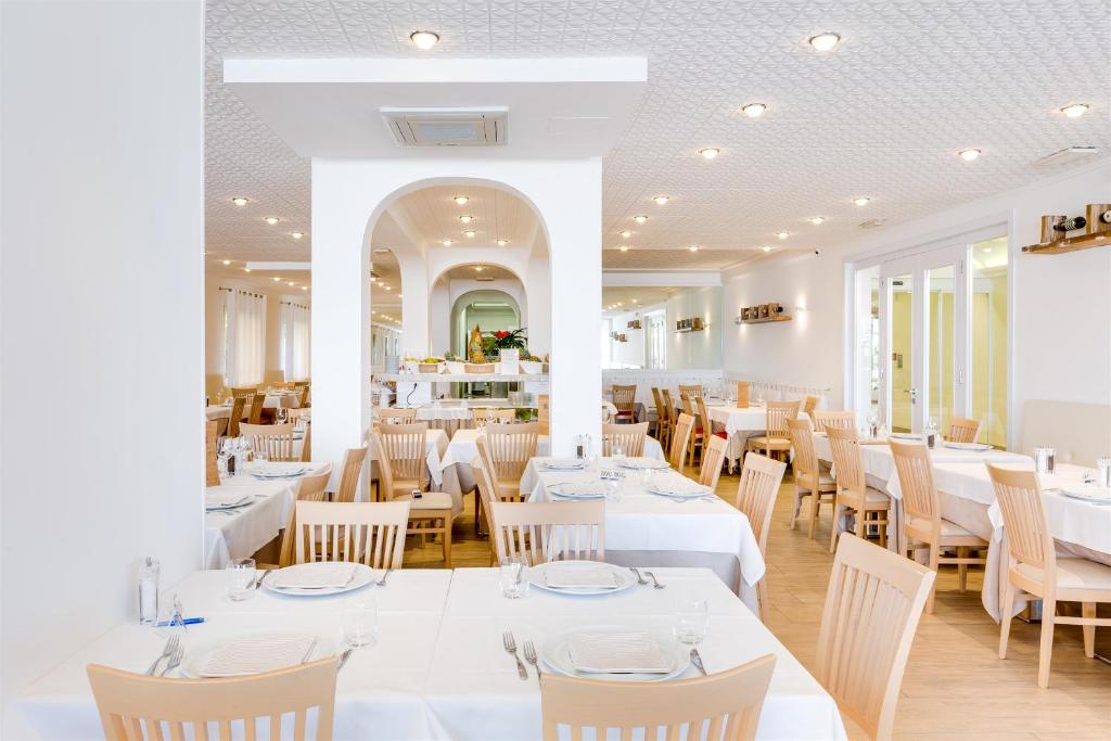 une salle à manger avec des tables et des chaises blanches dans l'établissement Hotel Bellariva, à Lido di Jesolo