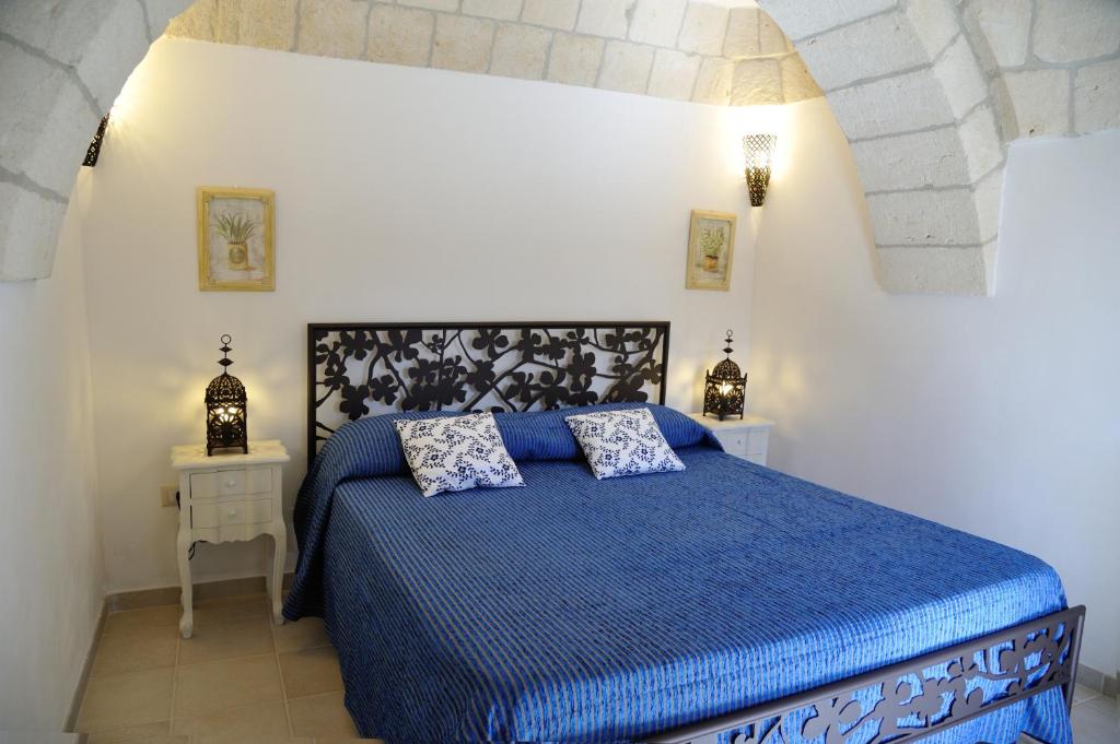 - une chambre avec un lit bleu et 2 tables de chevet dans l'établissement Trullo delle Querce Suite Private Pool, à Martina Franca