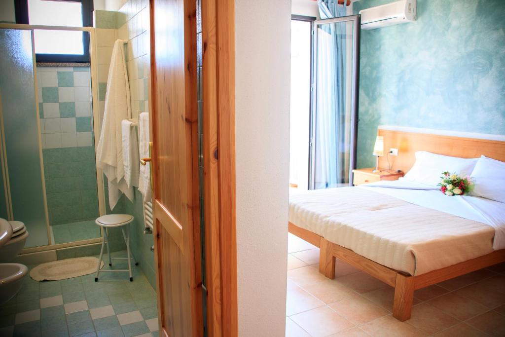 une chambre avec un lit et une salle de bain avec douche dans l'établissement Abbaidda Hotel, à Valledoria