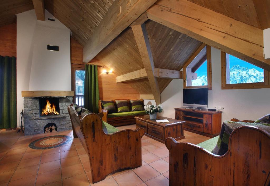 un salon avec un canapé et une cheminée dans l'établissement Chalet des Neiges Oz en Oisans, à Oz