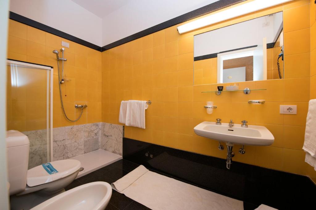 La salle de bains jaune est pourvue d'un lavabo et de toilettes. dans l'établissement Hotel Campagna, à Cannobio 35 autres photos