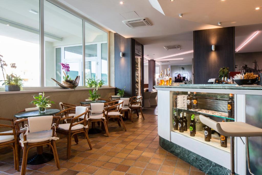 un restaurant avec un bar, des tables et des chaises dans l'établissement Hotel Ambassador, à Bibione
