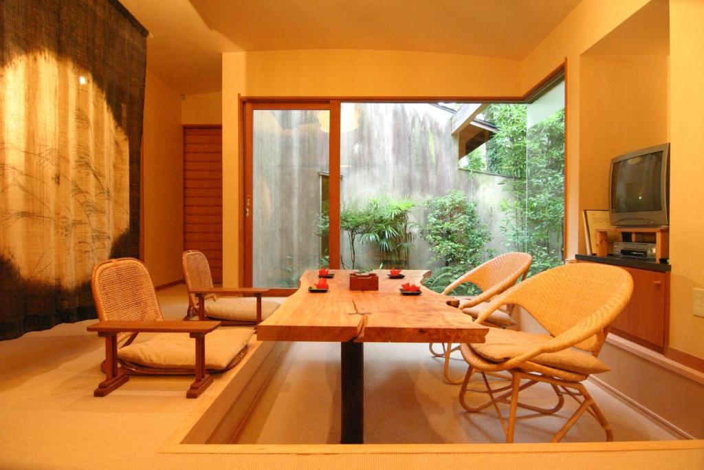 - un salon avec une table, des chaises et une télévision dans l'établissement Hanafubuki, à Itō