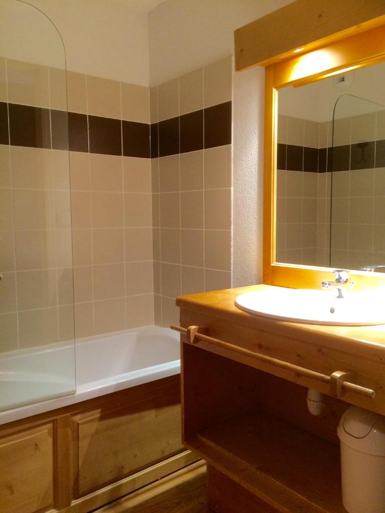 une salle de bain avec un lavabo, une baignoire et un miroir dans l'établissement Vacancéole - Résidence Central Park, à La Foux 20 autres photos