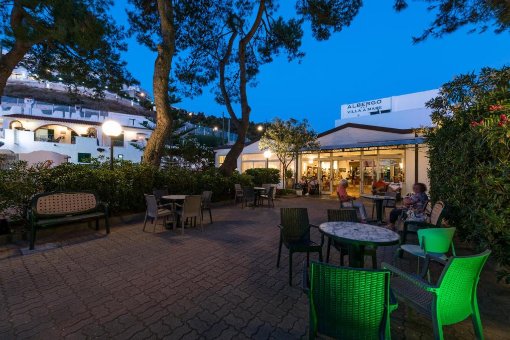 - une terrasse avec des tables et des chaises la nuit dans l'établissement Albergo Villa A Mare, à Peschici