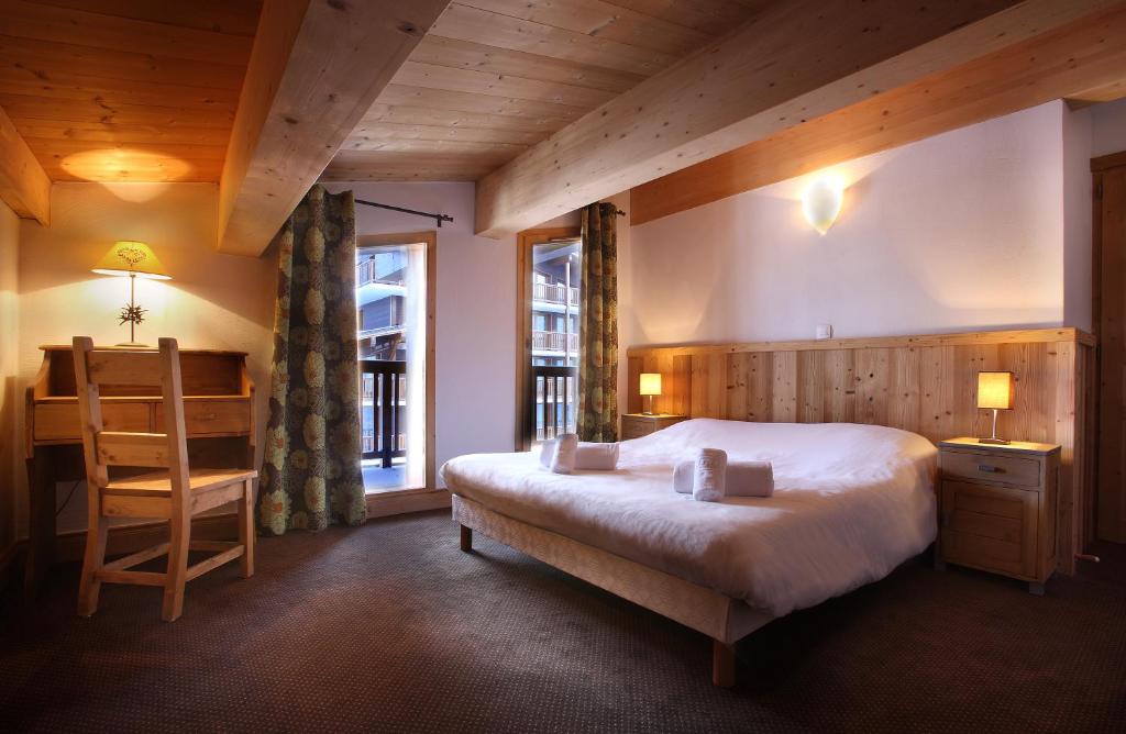 une chambre avec un lit, une table et une chaise dans l'établissement Chalet des Neiges : La Cime Des Arcs, à Arc 2000