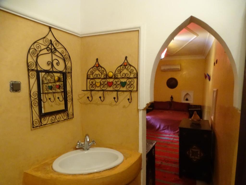 une salle de bain avec un lavabo et une chambre avec un lit dans l'établissement Riad Jakoura, à Marrakech