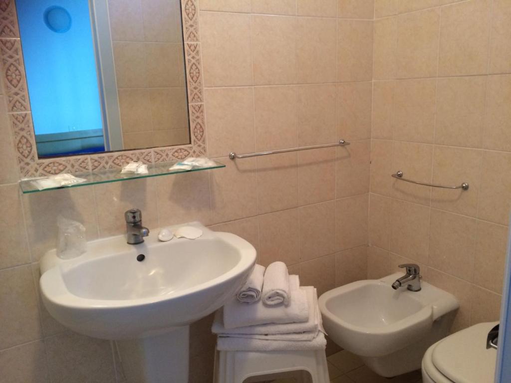 une salle de bain avec un lavabo, des toilettes et un miroir dans l'établissement Hotel Mercedes, à Misano Adriatico