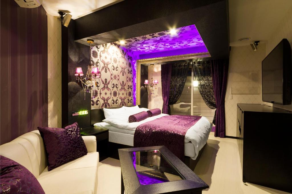 une chambre violette avec un lit et un canapé dans l'établissement Hotel Tosu Tsukasa (Love Hotel), à Tosu