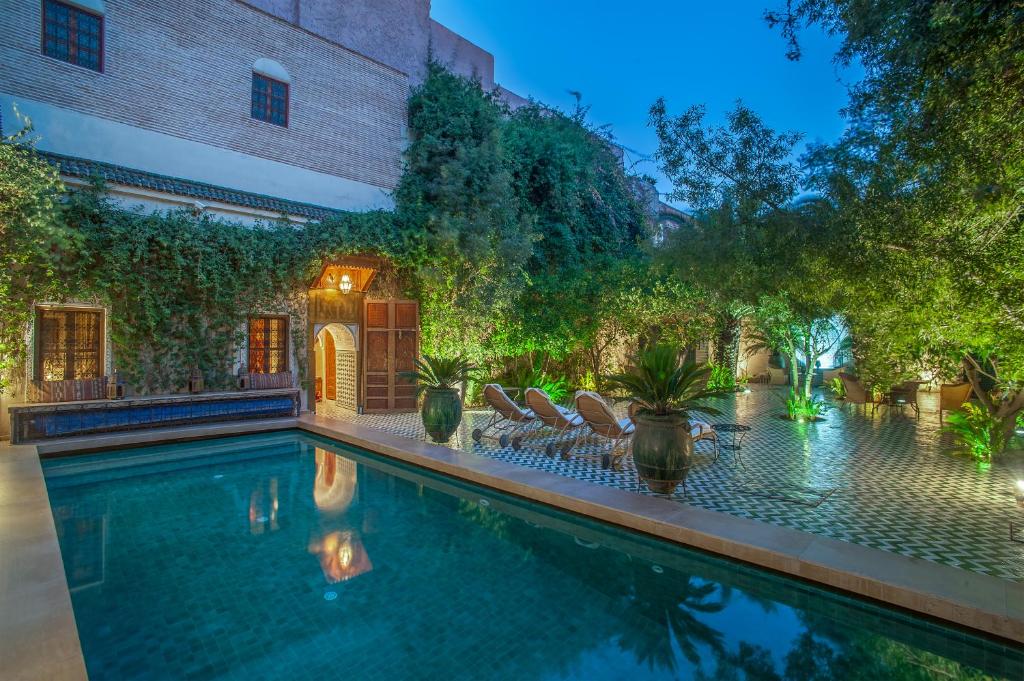 - une piscine dans un jardin avec des chaises et des arbres dans l'établissement Riad & Spa Laurence Olivier, à Marrakech