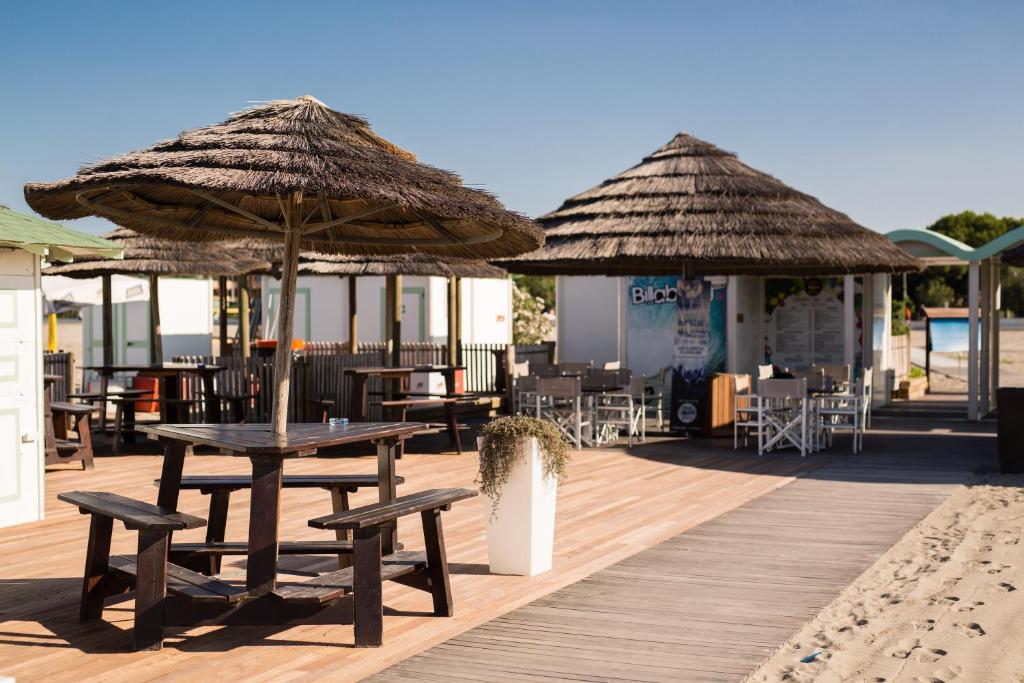 une terrasse avec des tables et des parasols sur une promenade dans l'établissement Laguna Palace Hotel Grado, à Grado