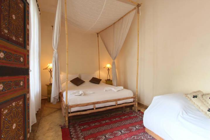 - une chambre avec deux lits et un lit à baldaquin dans l'établissement Riad Al Faras, à Marrakech